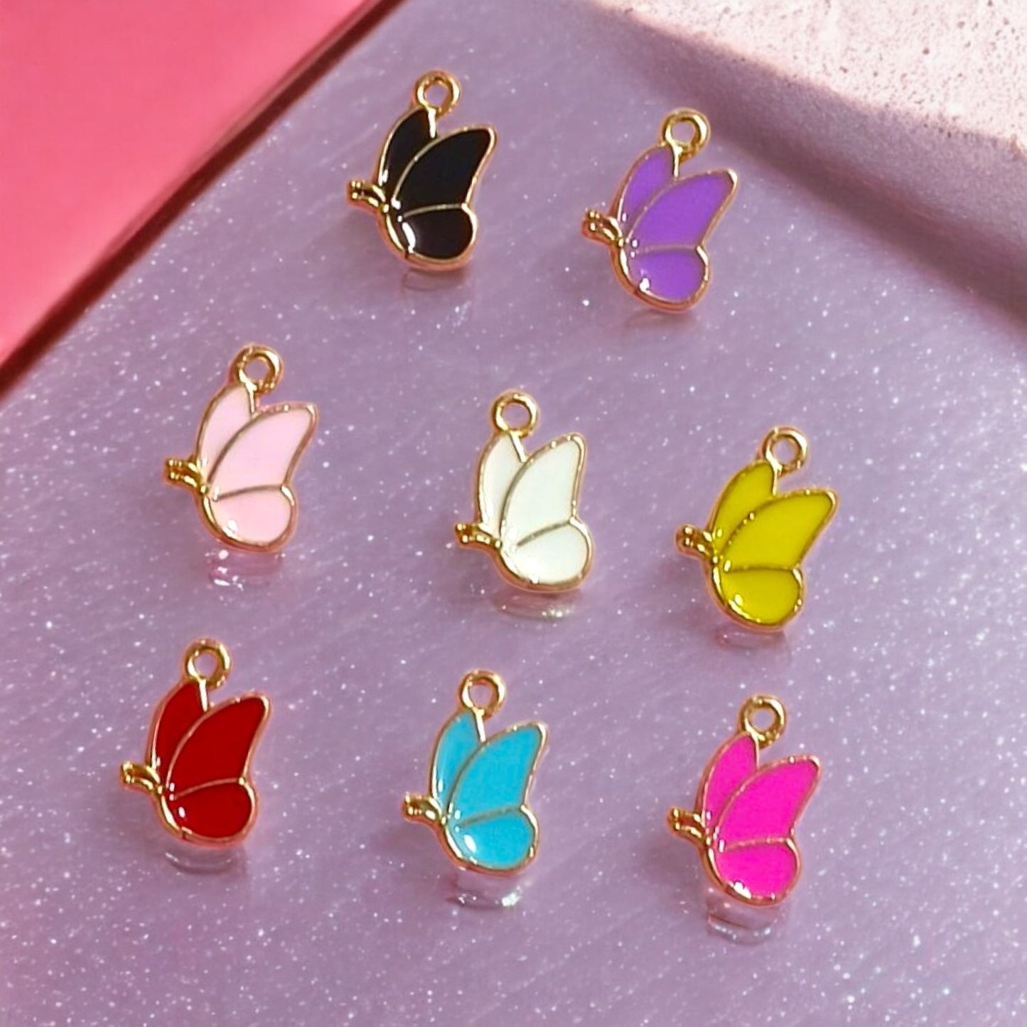 Butterfly wing-shaped enamel charms with vibrant colors and metallic trim, ideal for jewelry and craft making.