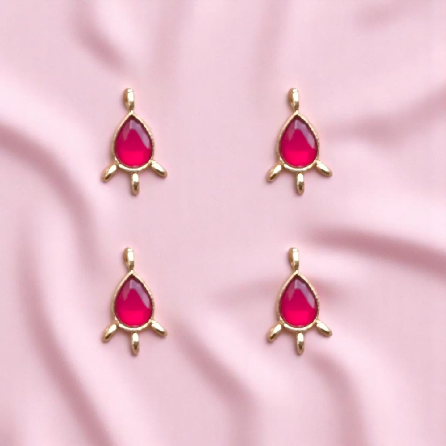Elegant red-colored Kundan drop connectors with teardrop shapes and metallic gold frames, perfect for linking elements in necklaces, earrings.