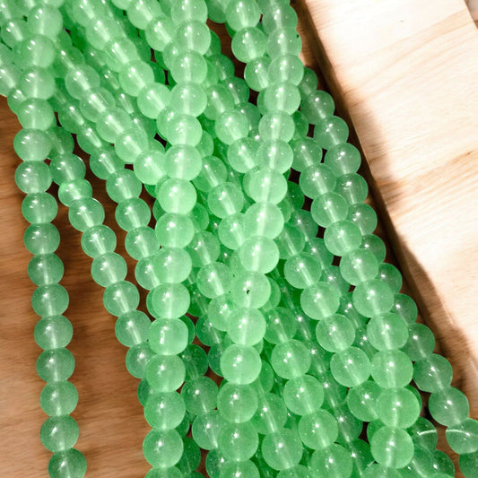 Translucent pista green jelly beads with a smooth, glossy surface, evenly shaped and slightly rounded, arranged in a line for jewelry crafting or DIY accessories