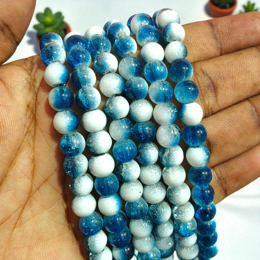 A strand of approximately 8 mm round beads in teal‑blue and milky white, each with a crackled interior visible through translucent glass that refracts light for a sparkling, marbled look